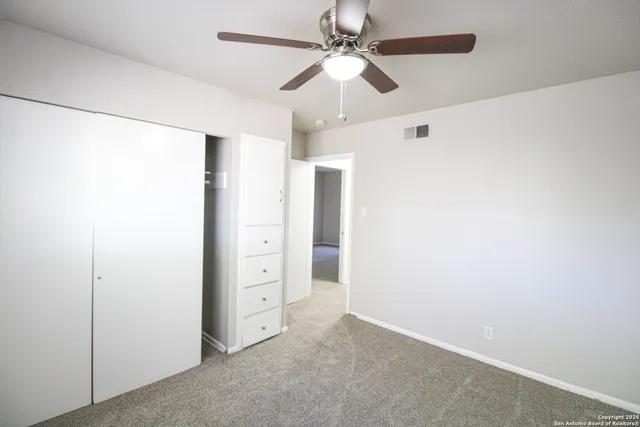 an empty room with closet and fan