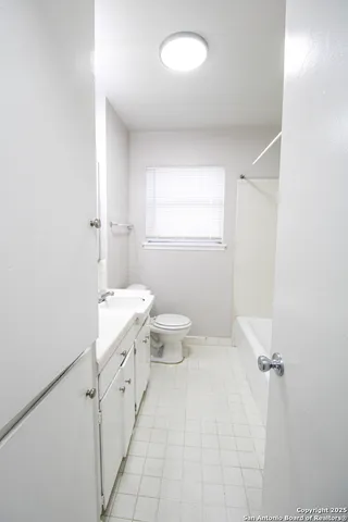 a bathroom with a granite countertop sink a toilet and a window