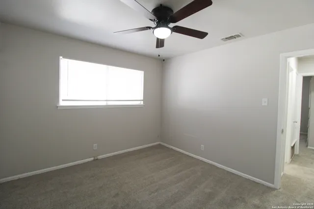an empty room with a window and a fan