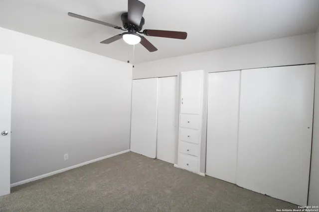 an empty room with a ceiling fan and a window