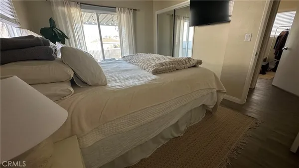 a bedroom with a bed next to a large window with wooden floor