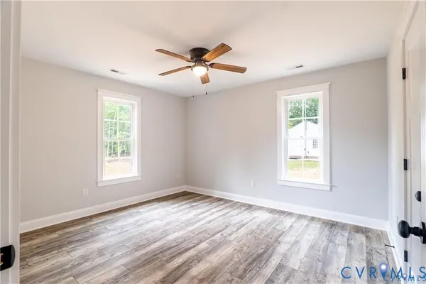 a view of an empty room with wooden floor and a window