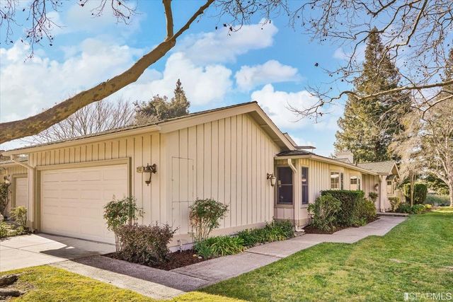 a front view of a house with a garden and tree