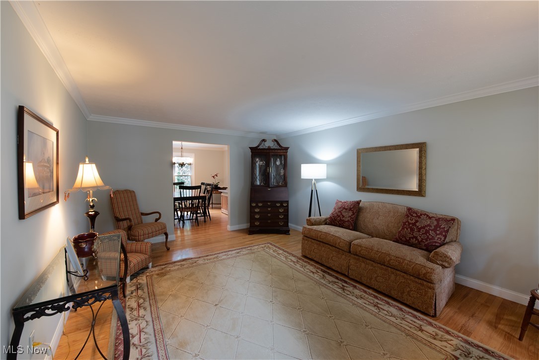 28314 Knickerbocker Road Bay Village, OH 44140 - Photo 17 of 38 Living room with an inviting chandelier, light hardwood / wood-style floors, and ornamental molding