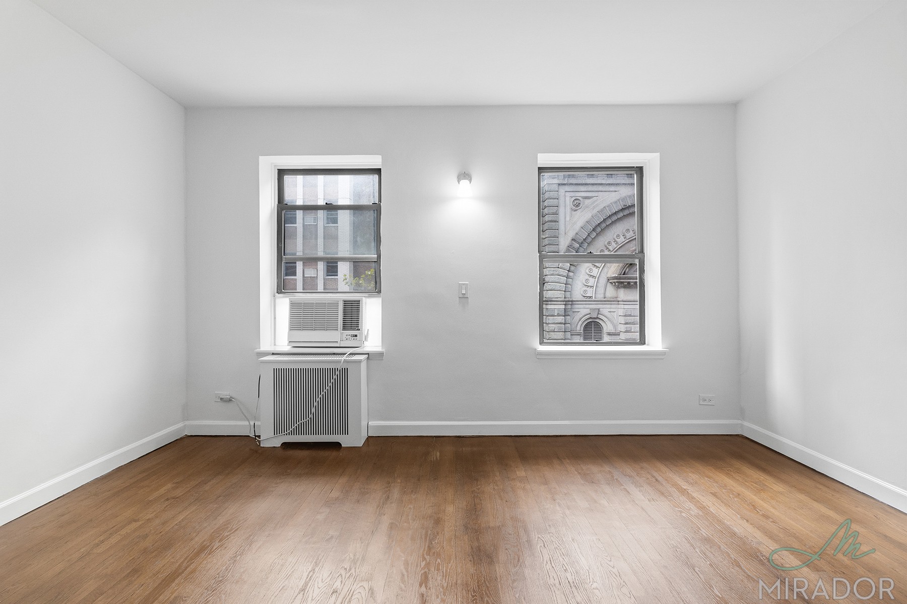 39 West 16th Street, Unit 5F Manhattan, NY 10011 - Photo 3 of 11 an empty room with wooden floor and windows