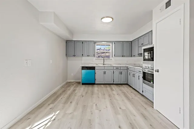 a kitchen with stainless steel appliances a sink and wooden floor