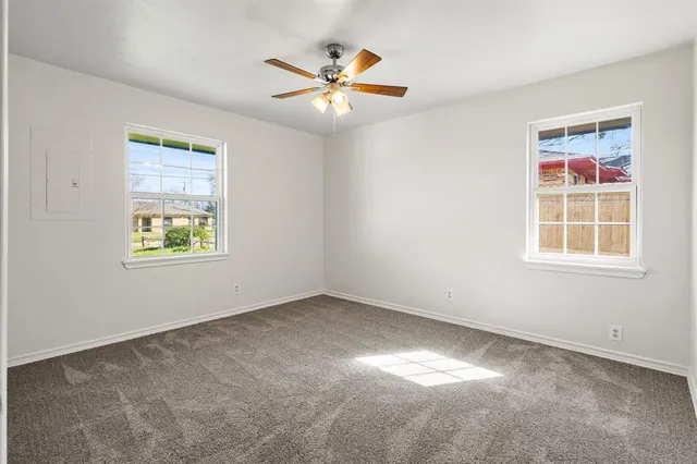 an empty room with window and ceiling fan