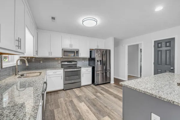 a living room with furniture kitchen view and a wooden floor