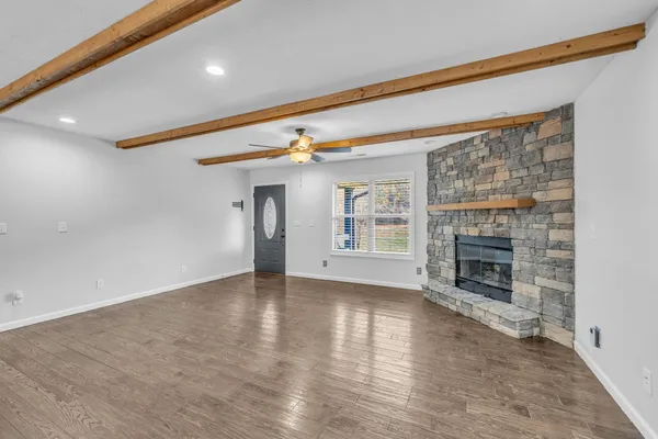 a view of an empty room with wooden floor and a kitchen