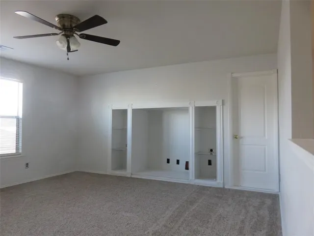 an empty room with windows and fan