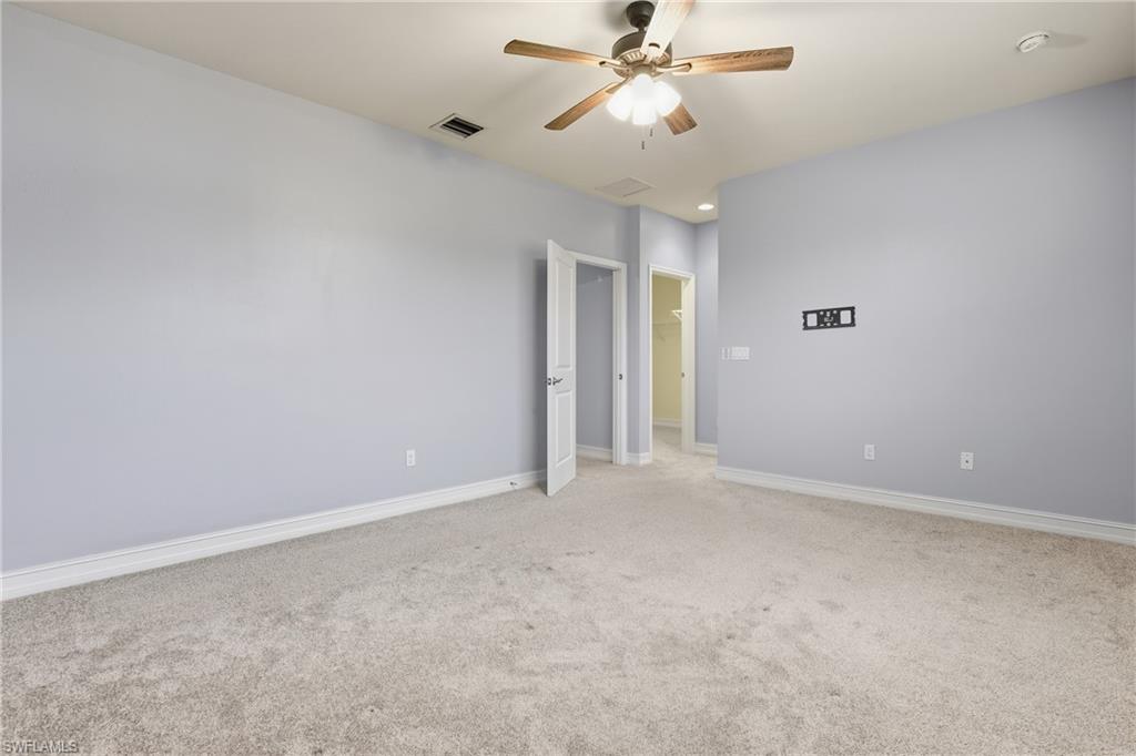 7894 Bristol Circle Naples, FL 34120 - Photo 14 of 29 an empty room with a chandelier fan and windows