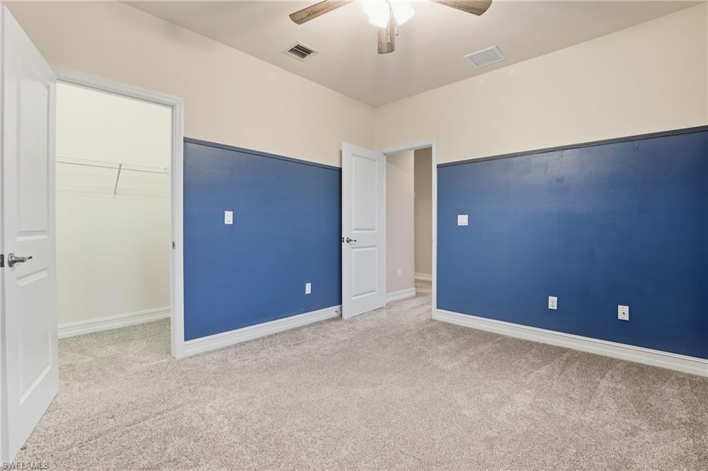 7894 Bristol Circle Naples, FL 34120 - Photo 21 of 29 en empty room with windows and chandelier fan