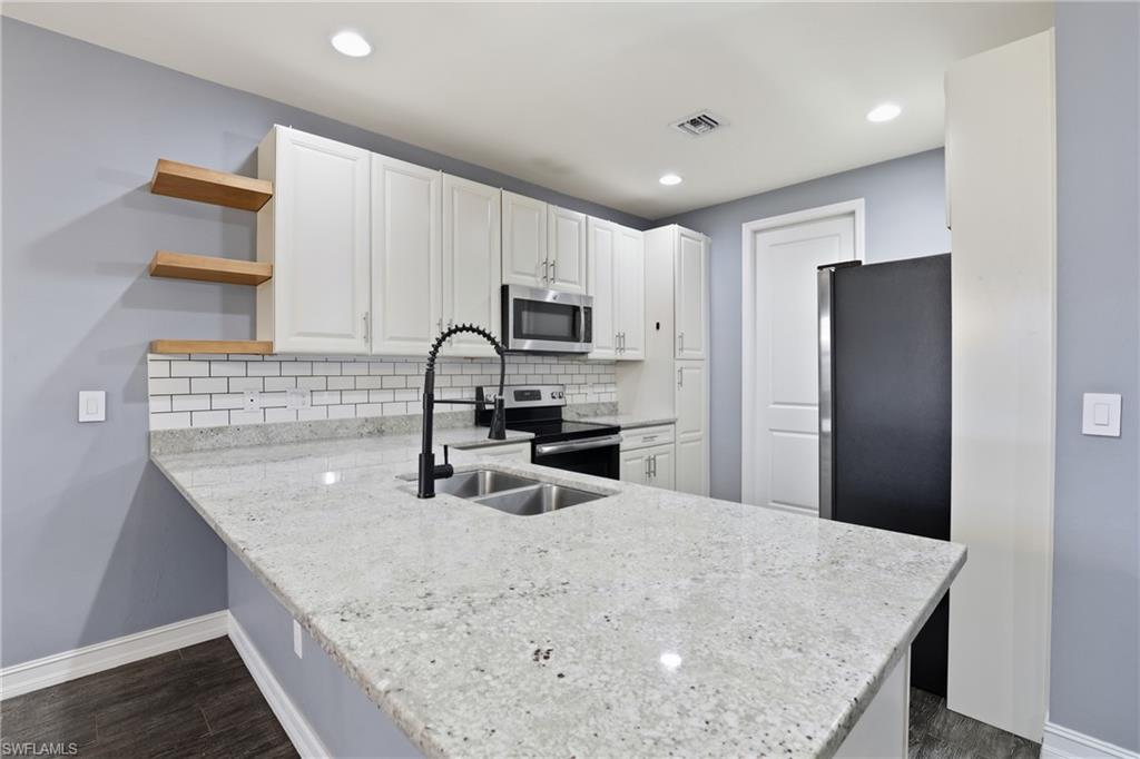 7894 Bristol Circle Naples, FL 34120 - Photo 8 of 29 a kitchen with stainless steel appliances granite countertop a sink a microwave a refrigerator and white cabinets