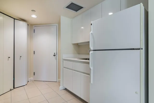 a view of a refrigerator in kitchen and an empty room