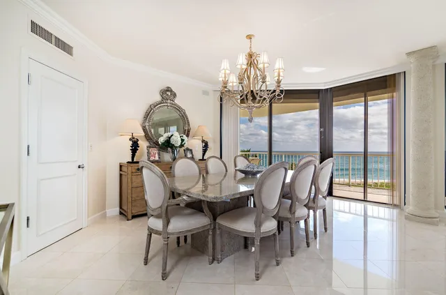 a view of a dining room with furniture a chandelier and large window