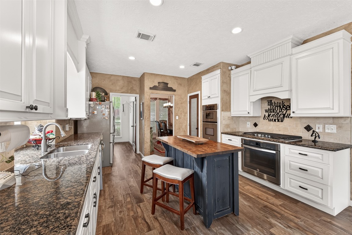 3506 Hunstanton Court Katy, TX 77450 - Photo 21 of 50 a kitchen with stainless steel appliances granite countertop a stove top oven a sink dishwasher and white cabinets with wooden floor