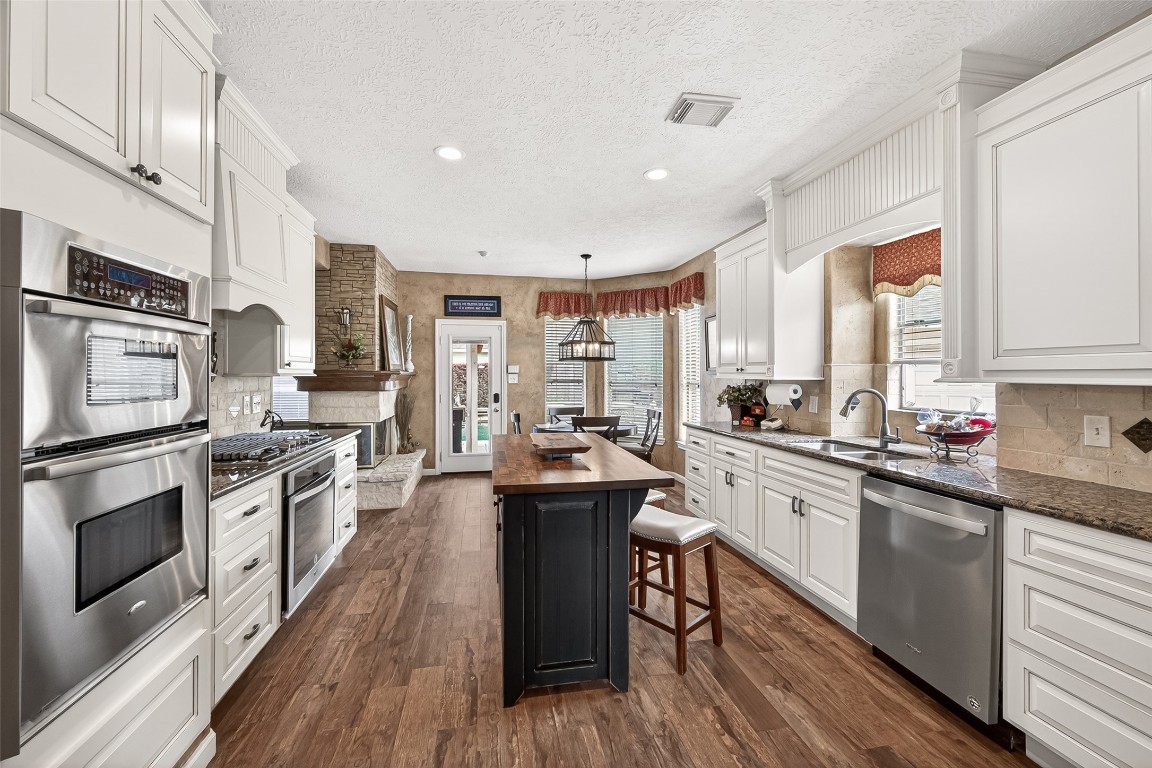 3506 Hunstanton Court Katy, TX 77450 - Photo 22 of 50 a kitchen with stainless steel appliances kitchen island granite countertop a stove a sink dishwasher and a microwave oven with wooden floor