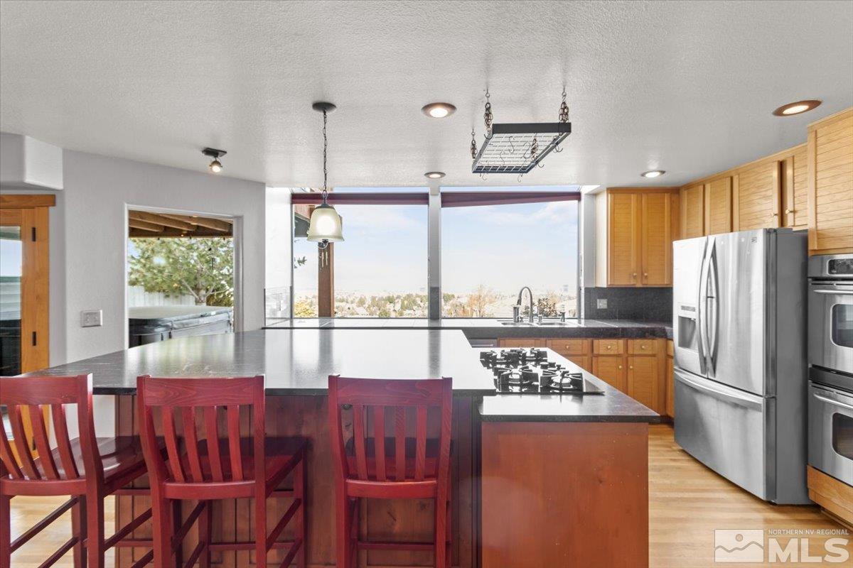 2616 Starr Meadows Loop Reno, NV 89519 - Photo 13 of 39 a kitchen with a refrigerator a stove and a dining table with wooden floor