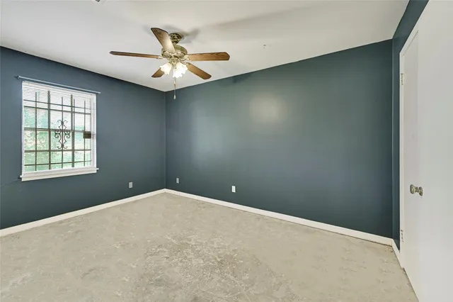 en empty room with window and ceiling fan
