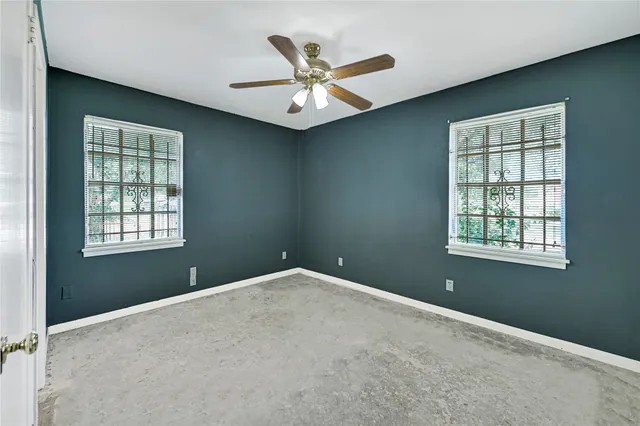 an empty room with ceiling fan and window