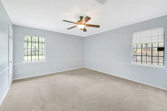 an empty room with windows and ceiling fan