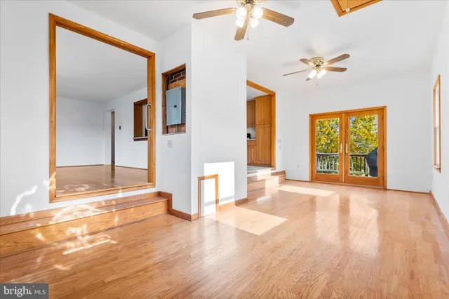 a view of an empty room with chandelier fan and fire place