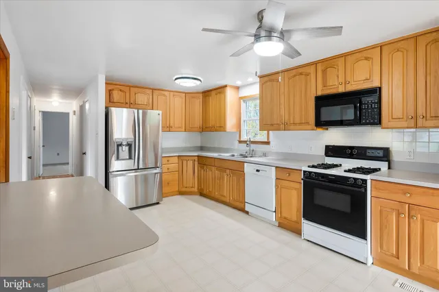 a kitchen with stainless steel appliances granite countertop a refrigerator a stove a sink a microwave oven with a dining table and chairs