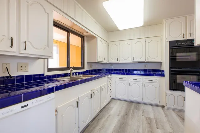 a kitchen with granite countertop white cabinets and white appliances