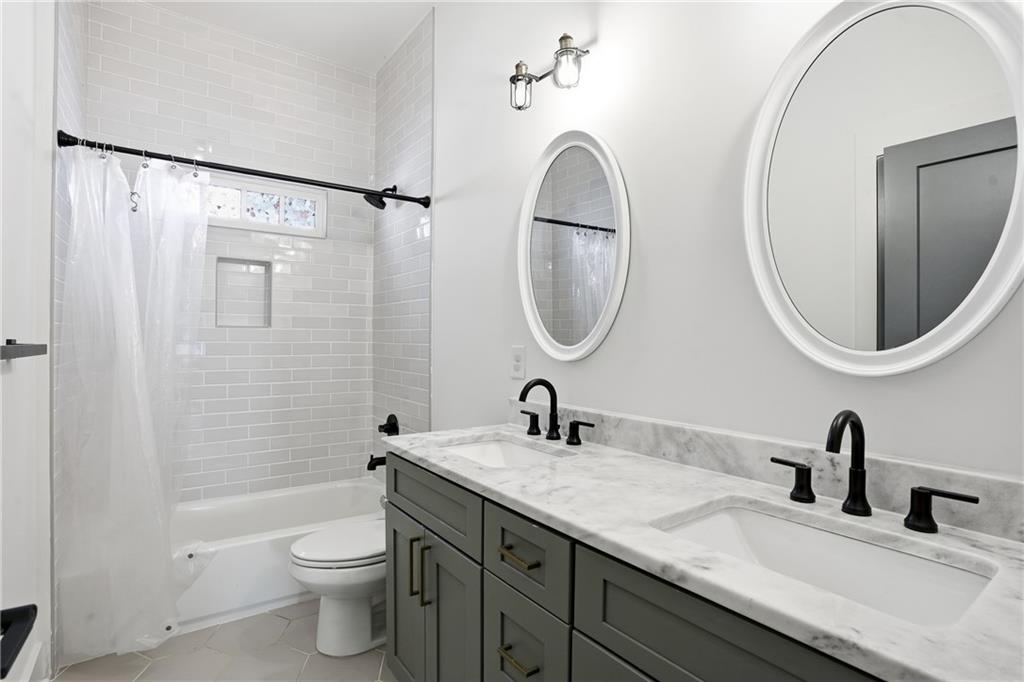1025 Oak Street Southwest Atlanta, GA 30310 - Photo 22 of 30 a bathroom with a granite countertop toilet a sink and a mirror