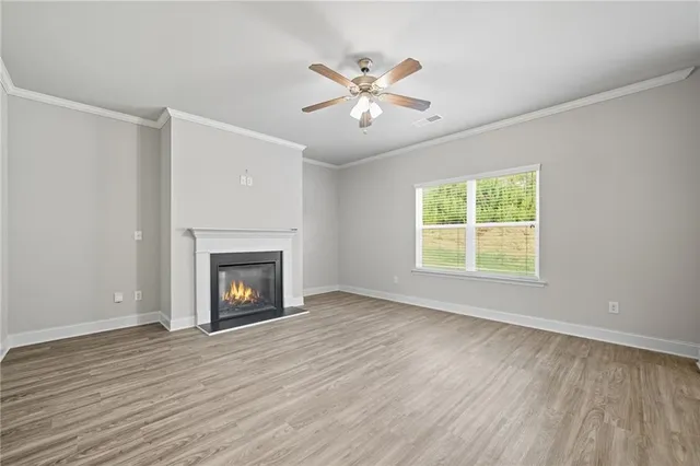 an empty room with wooden floor fireplace and windows