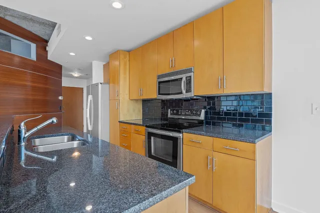 a kitchen with stainless steel appliances granite countertop a sink a stove and a refrigerator