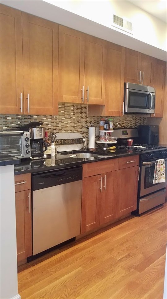 525 Adams Street, Unit 4L Hoboken, NJ 07030 - Photo 3 of 7 a kitchen with stainless steel appliances granite countertop a stove a sink and a microwave