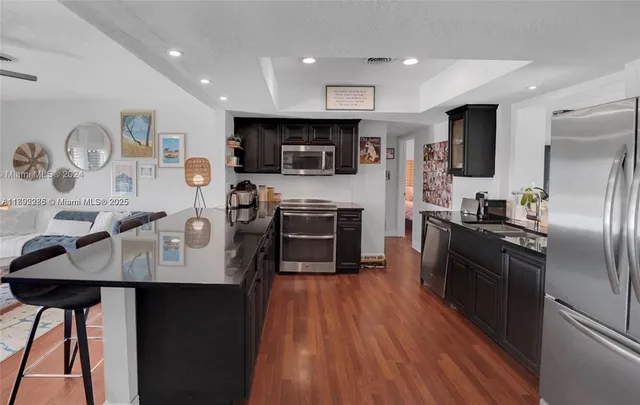 a kitchen with stainless steel appliances granite countertop a refrigerator a stove top oven a sink and dishwasher with wooden floor