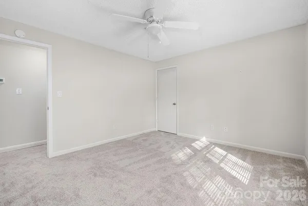an empty room with a fan & a ceiling fan