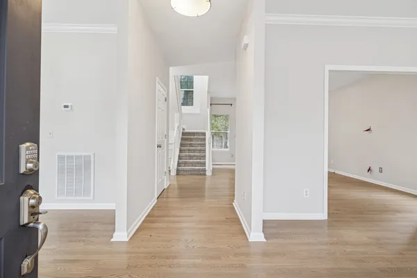 a view of an empty room with wooden floor and a window