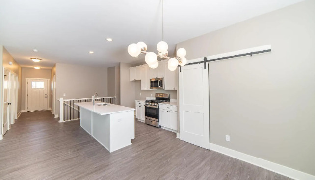 7235 Genesis Way Bettendorf, IA 52722 - Photo 15 of 26 a large kitchen with kitchen island a stove a sink dishwasher and a refrigerator with wooden floor