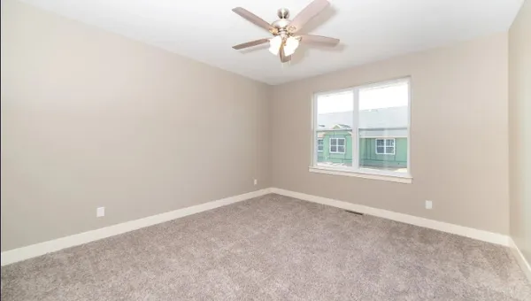 an empty room with windows and ceiling fan