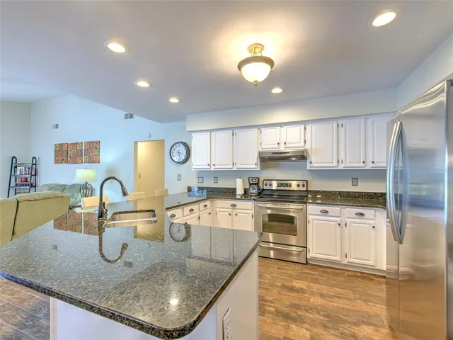 a kitchen with kitchen island granite countertop a stove and a sink