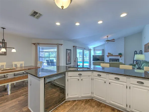 a kitchen with kitchen island granite countertop a sink cabinets and wooden floor