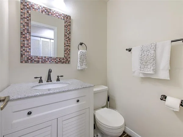 a bathroom with a granite countertop toilet sink mirror and vanity