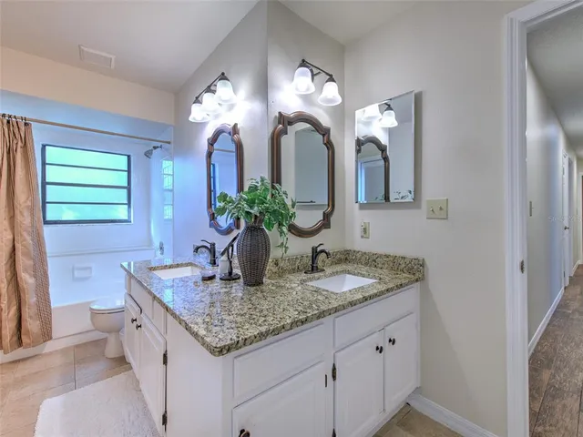 a bathroom with a granite countertop sink a light fixture and a mirror