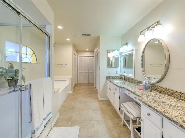 a large bathroom with a granite countertop double vanity sink a mirror and a shower