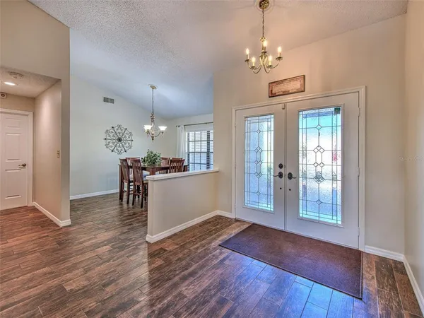 a dining room with wooden floor a chandelier a wooden table and chairs