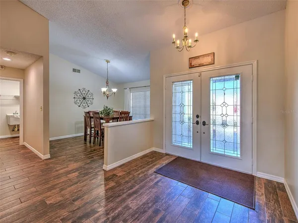 a view of a hallway with wooden floor and a kitchen