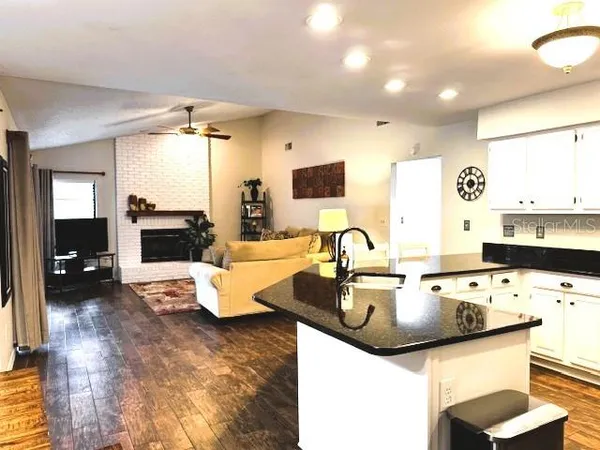 a kitchen with kitchen island a stove a sink a dining table and chairs with wooden floor