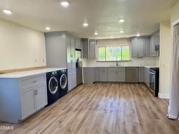 a view of kitchen with sink and cabinets wooden floor and window
