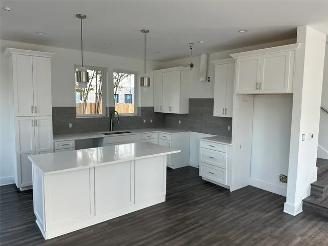 a large kitchen with granite countertop a white stove top oven and white cabinets