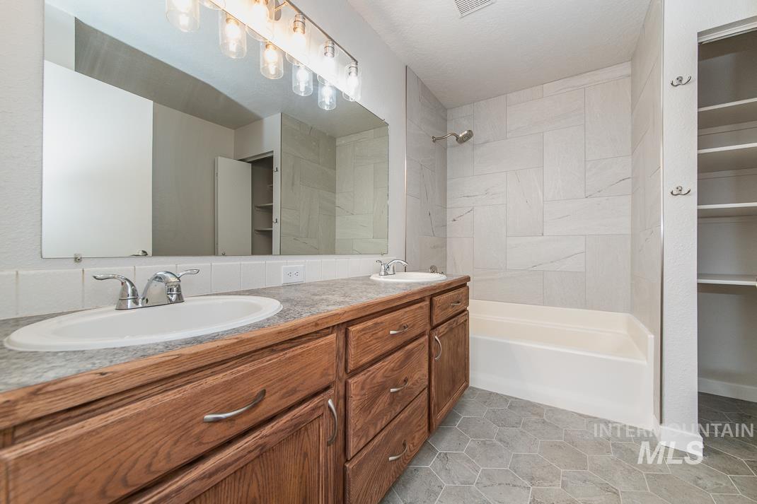 480 Easy Street Kuna, ID 83634 - Photo 19 of 39 Full bathroom featuring a spacious closet, double vanity, bathing tub / shower combination, and light tile patterned floors