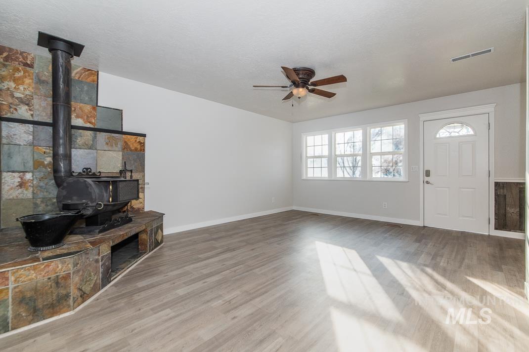 480 Easy Street Kuna, ID 83634 - Photo 26 of 39 Unfurnished living room featuring a wood stove, ceiling fan, and light wood finished floors
