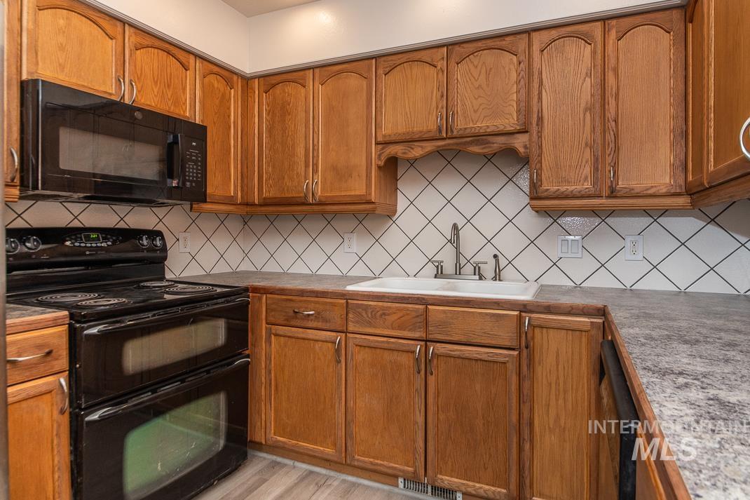 480 Easy Street Kuna, ID 83634 - Photo 29 of 39 Kitchen with black appliances, brown cabinetry, and decorative backsplash
